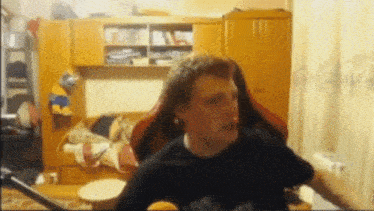 a man in a black shirt is sitting in a red chair in a living room