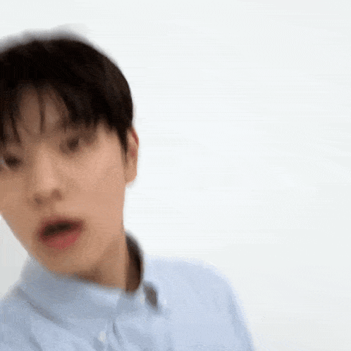 a blurry picture of a young man wearing a blue shirt and looking at the camera .