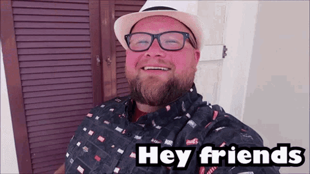 a man wearing glasses and a hat is smiling and says hey friends