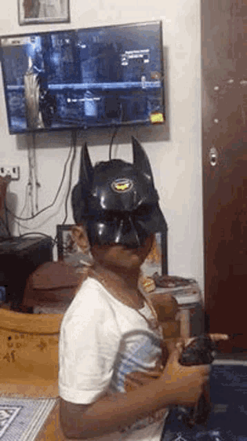 a boy wearing a batman mask is playing a video game .