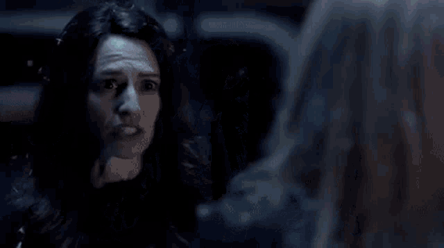a woman is standing next to a man in a dark room with snow falling .
