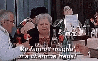 a group of people are sitting at a table with a woman holding a piece of paper that says ma famme magna
