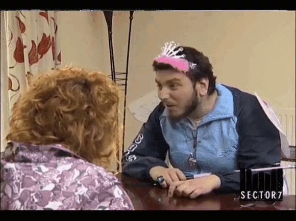 a man wearing a pink tiara sits at a table with a sign that says sector7