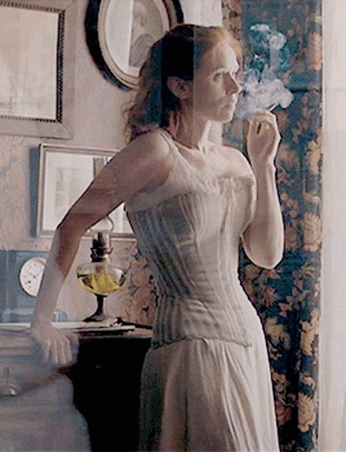 a woman in a corset is smoking a cigarette in a room