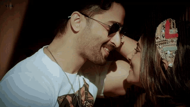 a man and a woman are kissing and the man is wearing sunglasses and a white shirt