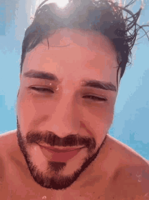 a shirtless man with a beard is smiling underwater