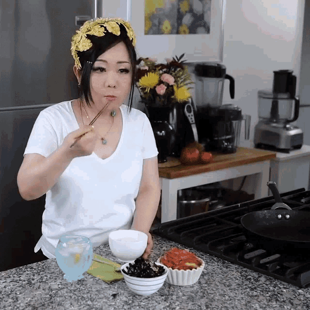 a woman wearing a flower headband is eating food with chopsticks