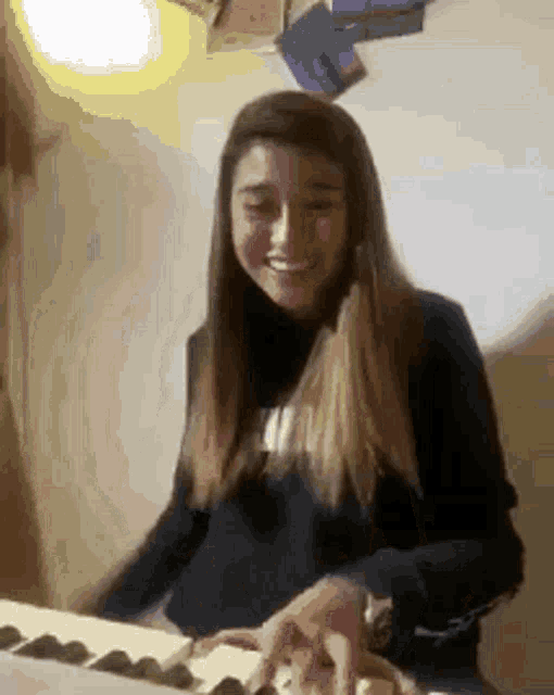 a woman is smiling while playing a keyboard in a room .