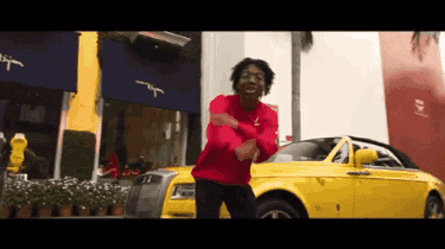 a man is dancing in front of a yellow car
