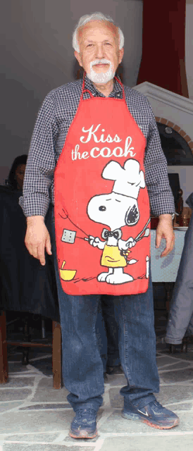 a man wearing a red apron that says kiss the cook on it