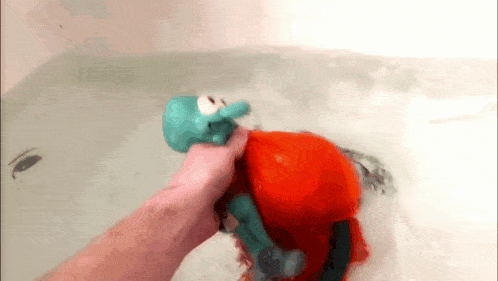 a person is holding a toy in a bathtub with water coming out of it .