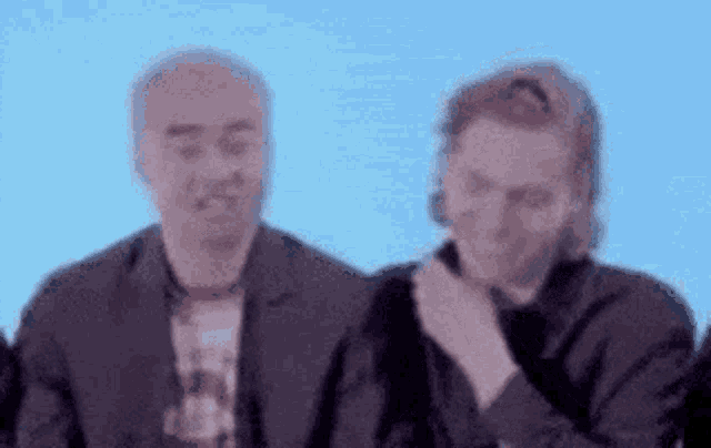 two men are standing next to each other on a blue background .