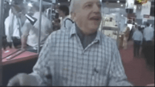 a man wearing a plaid shirt is standing in a crowded room
