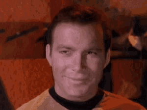 a close up of a man wearing a yellow shirt and a black collar making a funny face .