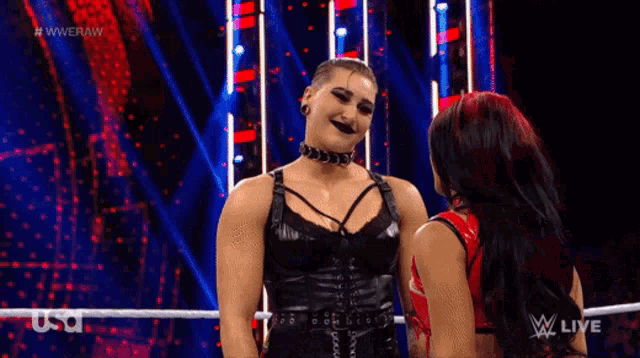 two women are hugging each other in a wrestling ring on a wrestling show .