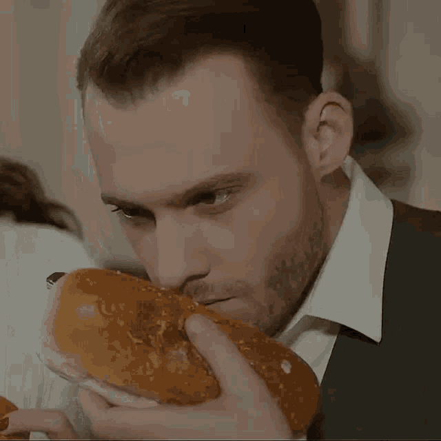 a man in a suit is eating a sandwich