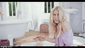 a woman is sitting in a bathtub holding a piece of pizza in her hand .