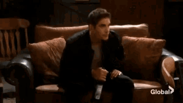 a man is sitting on a couch with a bottle of beer in his hand .