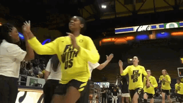 a woman in a yellow shirt that says fly with us is dancing