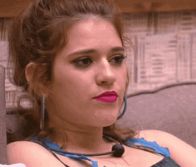 a close up of a woman 's face with pink lipstick and blue earrings