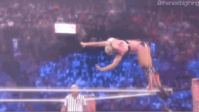 a referee is standing in a wrestling ring watching a wrestler throw a punch .