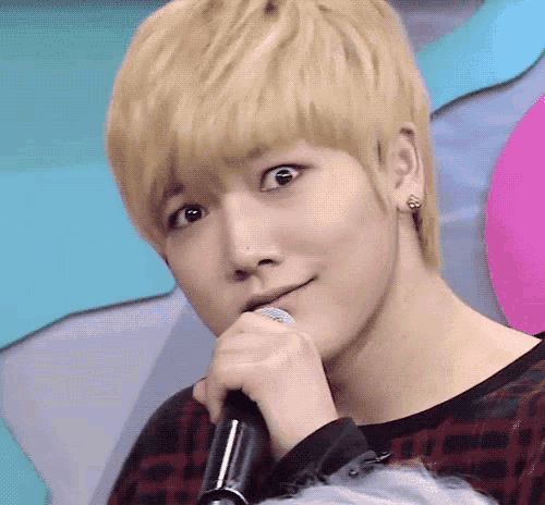 a young man with blonde hair is holding a microphone in his hand