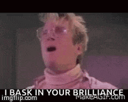 a man wearing glasses and a pink turtleneck says i bask in your brilliance