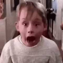 a young boy is making a surprised face with his mouth wide open .