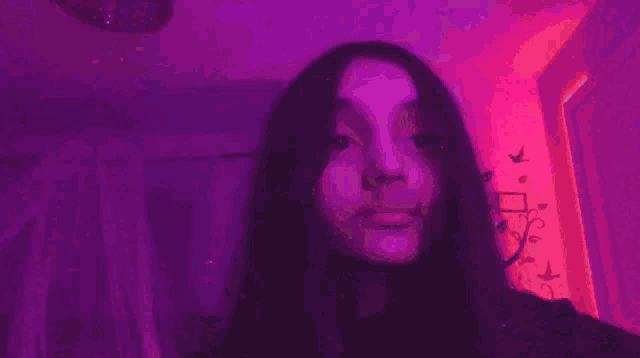 a girl is taking a selfie in front of a purple and pink light .