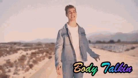 a man in a denim jacket stands on a dirt road with the words body talkin written below him