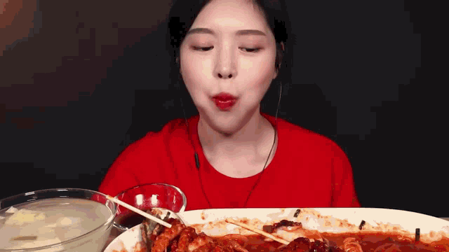 a woman in a red shirt is eating a large plate of food
