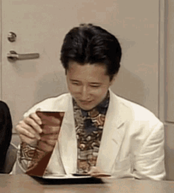a man in a suit and tie is sitting at a table holding a box .