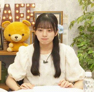a girl is sitting at a table with a teddy bear on a shelf .