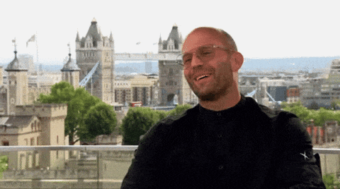 a man wearing sunglasses is laughing in front of a city skyline