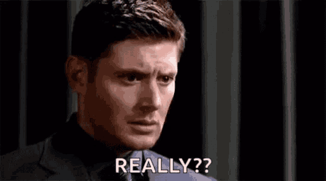 a man in a suit and tie is making a funny face and saying `` really '' .