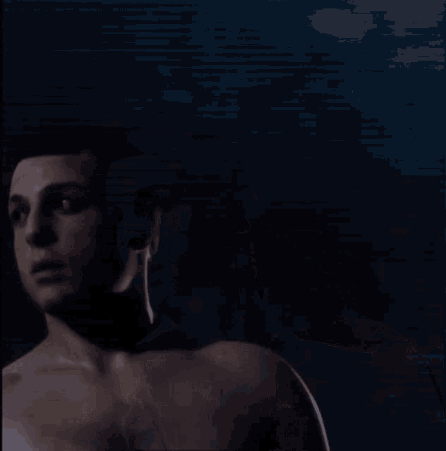 a man without a shirt is looking at something in the dark