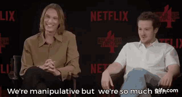 two men are sitting next to each other in front of a netflix sign and talking .
