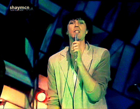 a man singing into a microphone with shaymcn on the bottom right