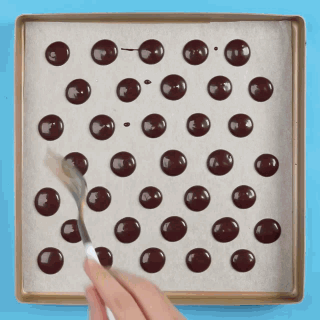 a person is spreading chocolate dots on a pan