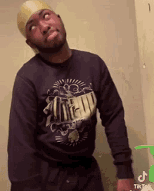 a man wearing a black shirt and a gold headband is standing next to a green bottle of soap .