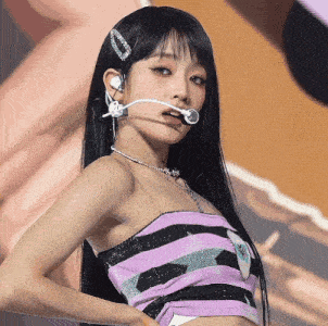 a woman with long black hair is wearing a purple and black striped top and headphones