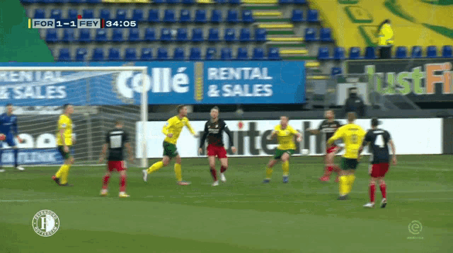 a soccer game is being played in front of a rental and sales advertisement