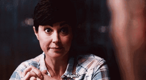 a woman is sitting at a table with her hands folded and asking a question .