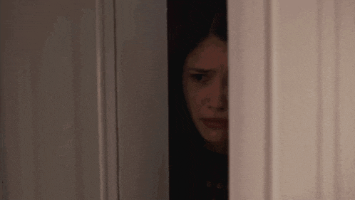 a close up of a woman 's face peeking out of a door .