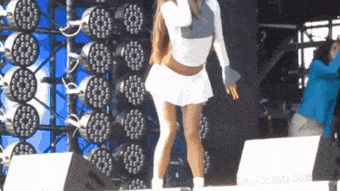 a woman in a white skirt stands on a stage