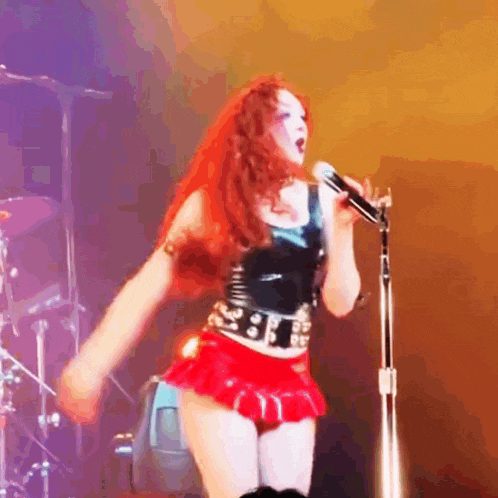a woman with red hair is singing into a microphone on a stage .