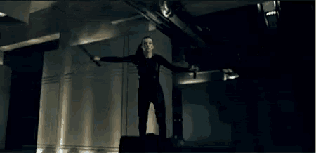 a woman is standing in a dark room holding a sword in her hand .