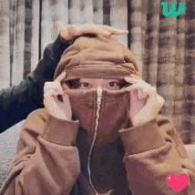 a woman wearing a hooded jacket is covering her face .