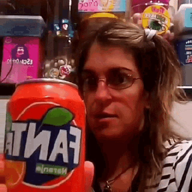 a woman holding a can of fanta in front of her face