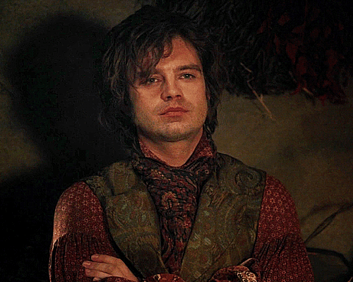 a man with long hair and a scarf around his neck is looking at the camera